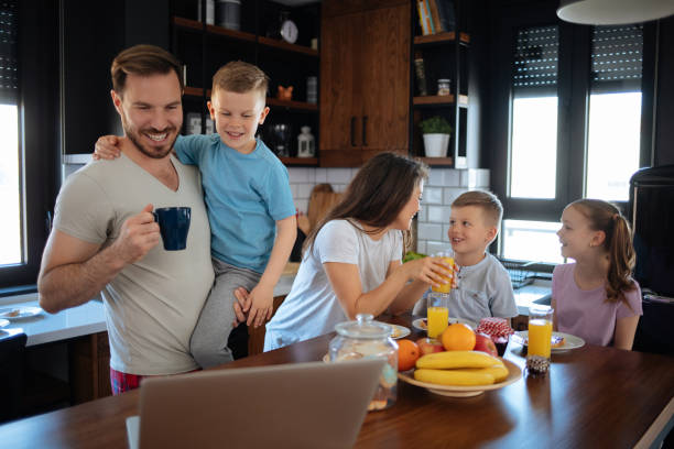 istock Father using laptop with son, family in background 1174424251