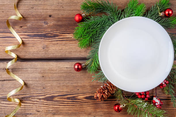 istock Christmas plate, pine branches with christmas decorations on wooden background 1174424572