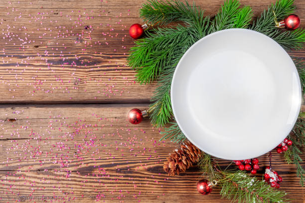 istock Christmas plate, pine branches with christmas decorations on wooden background 1174424639