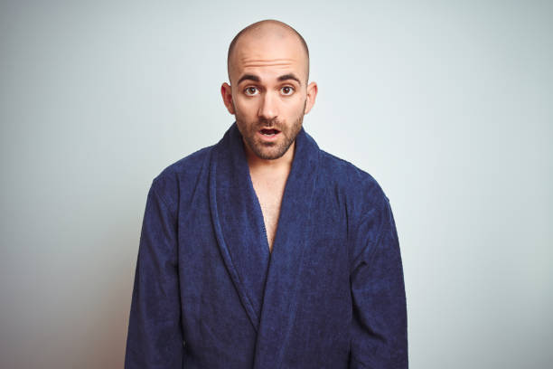 istock Young man wearing blue bathrobe, relaxed lifestyle over isolated background afraid and shocked with surprise expression, fear and excited face. 1174425582