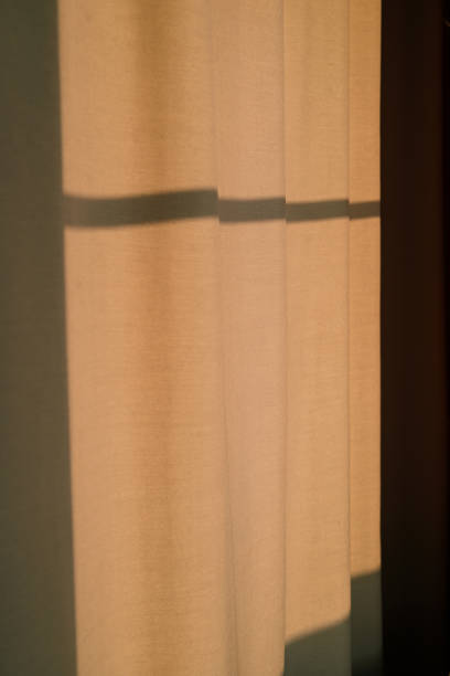 istock Strong shadows fall on curtains at sunset light. Modern minimal design in beige 1174425930