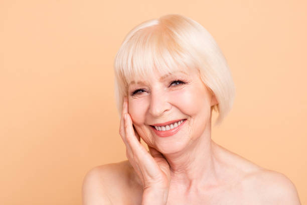 close-up portrait of nice attractive sweet groomed cheerful cheery positive gray-haired lady touching perfect flawless sensitive skin instant positive effect hydration isolated over beige background - women tan perfection naked imagens e fotografias de stock