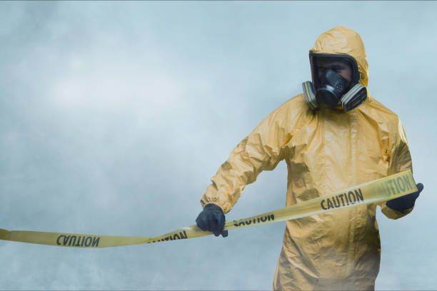 Worker in protective suit with cordon tape Worker wearing yellow protective suit holding warning tape medical alarm stock pictures, royalty-free photos & images