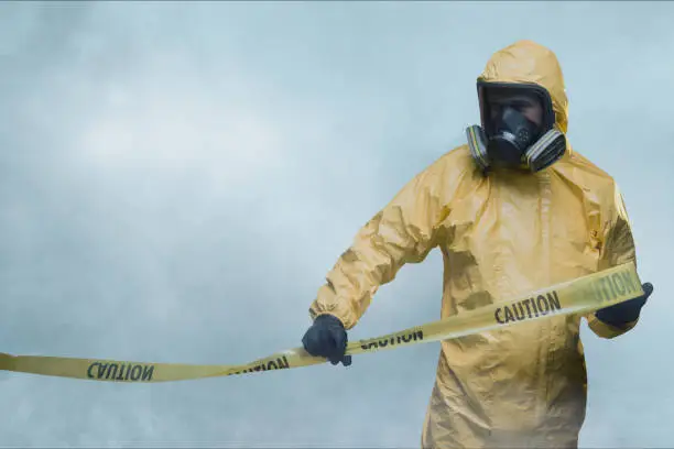 Photo of Worker in protective suit with cordon tape