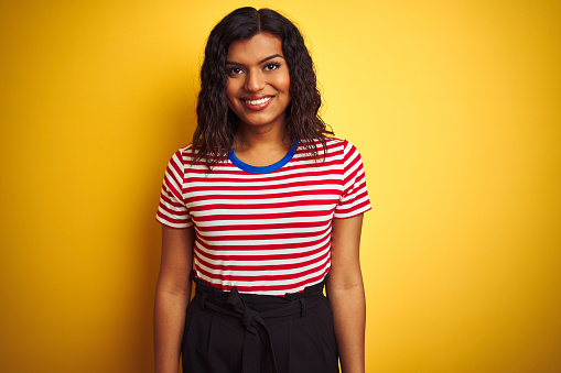 Transsexual transgender woman wearing stiped t-shirt over isolated yellow background with a happy and cool smile on face. Lucky person.