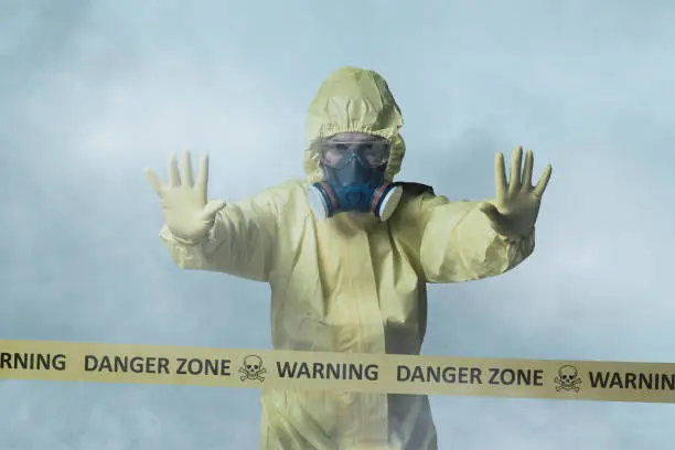 Photo of Worker in protective suit showing stop gesture