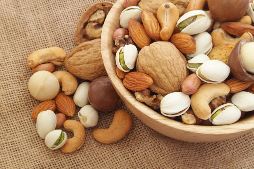 Many mixed nuts, walnuts, cashews, almonds, macadamia nuts, pistachios, peanuts in wooden bowl