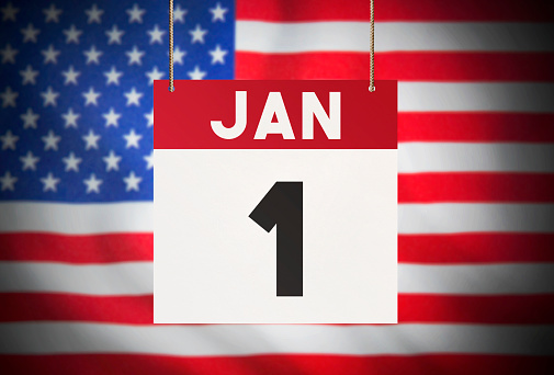 Calendar standing in front of the American flag and showing JAN 1 Stock Image