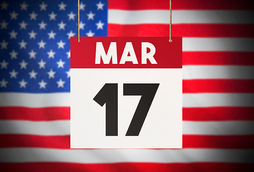 Calendar standing in front of the American flag and showing March 17 Stock Image