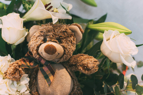 istock teddy bear and a bunch of white flowers 1174431651