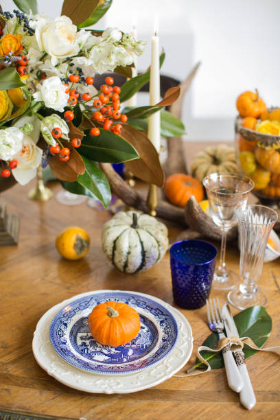 istock Luxurious elegant wedding decor in autumn style. Wooden vintage table setting with ceramic plates and silver cutlery. Fresh flowers in a vase, orange pumpkins, deer horns and candles. Romantic dinner. 1174433012