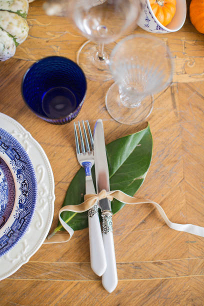 istock Luxurious elegant wedding decor in autumn style. Wooden vintage table setting with ceramic plates and silver cutlery. Fresh flowers in a vase, orange pumpkins, deer horns and candles. Romantic dinner. 1174433028