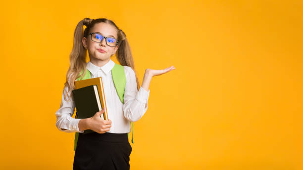 istock Dissatisfied First-Grade School Girl Shrugging Shoulders In Studio 1174433197