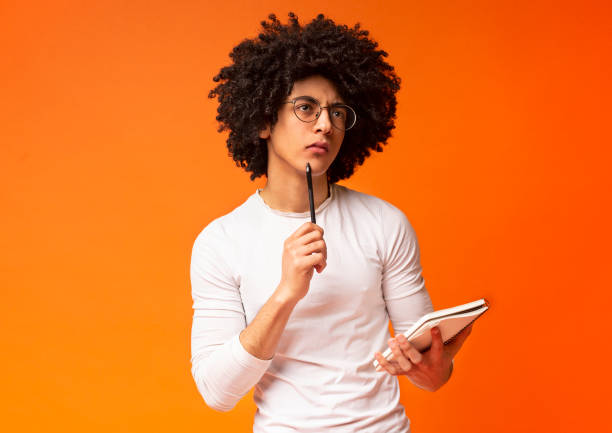istock Pensive black guy brainstorming with notebook and pencil 1174433505