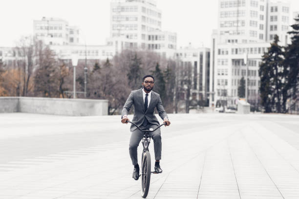 istock Afro man in suit riding bicycle on the way to office 1174433598