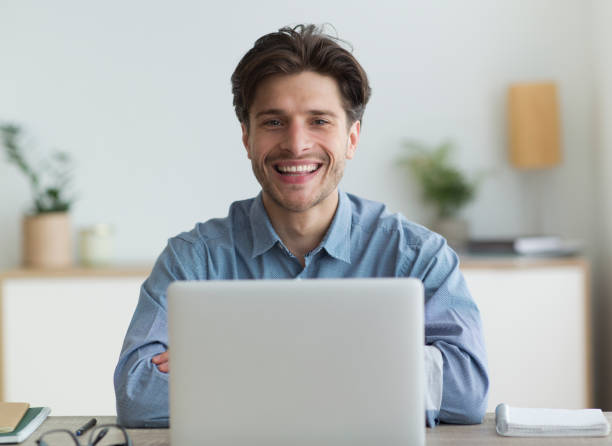 istock Freelance Guy Smiling At Camera Sitting At Laptop In Office 1174434763