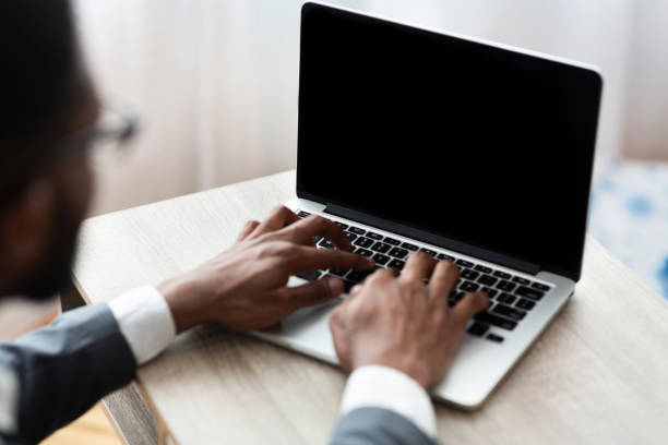 istock Black businessman typing on laptop with blank screen 1174434834
