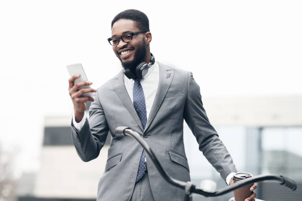 istock Happy businessman using phone, standing with bicycle 1174434971