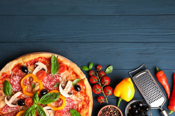 istock Delicious pizza and ingredients on wooden background, copy space 1174435371