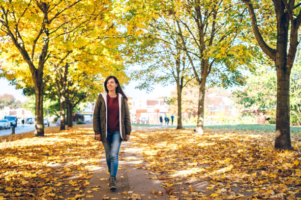 donna che cammina in un parco - autumn women park people foto e immagini stock