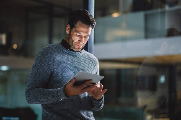 The internet is an open source of information Cropped shot of a handsome mature businessman standing alone in his office and using a tablet marco dapper stock pictures, royalty-free photos & images