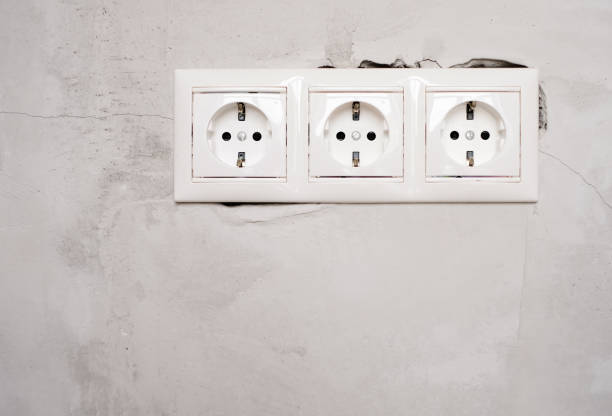 Electric EU socket outlet on gray concrete wall background. Repair in an apartment or in office, replacement of electrical wiring. Close up view. stock photo