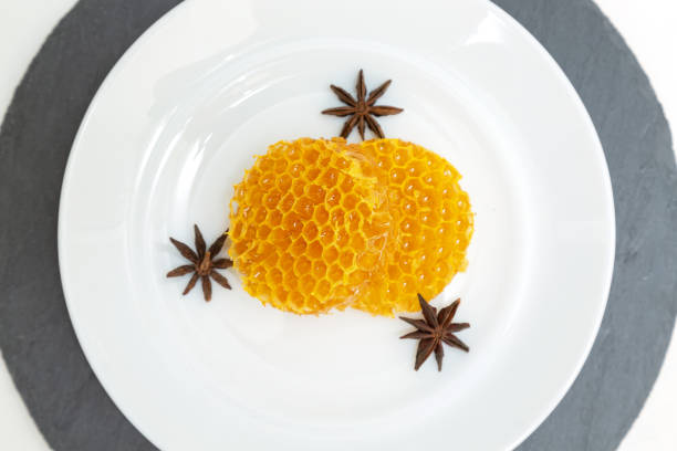 istock Round honeycombs lie on a plate on a white wooden background. 1174439764