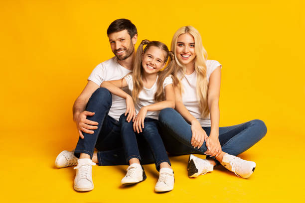 istock Parents And Daughter Hugging Sitting On Yellow Background 1174439895