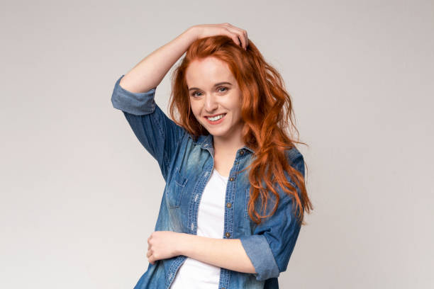 istock Shy Ginger Girl Touching Hair While Posing On Camera 1174440485