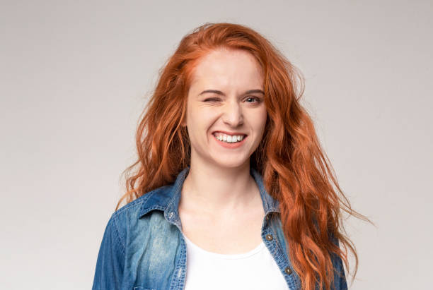 istock Pretty young ginger girl winking over light background 1174440563