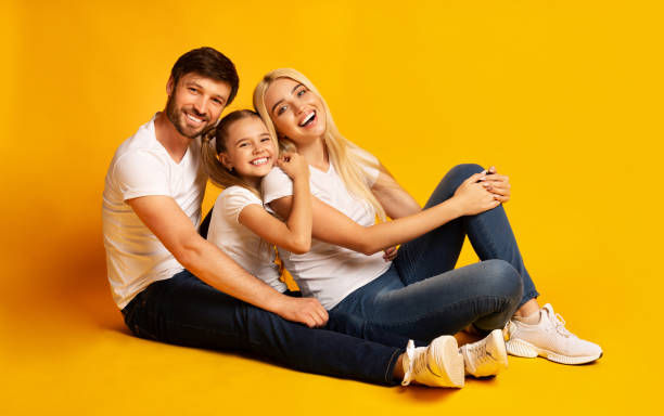 istock Parents And Daughter Hugging Sitting On Floor In Studio 1174441175
