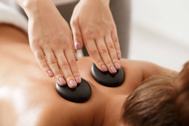 mujer relajada recibiendo masaje de hombros de piedras en spa - massage stones fotografías e imágenes de stock