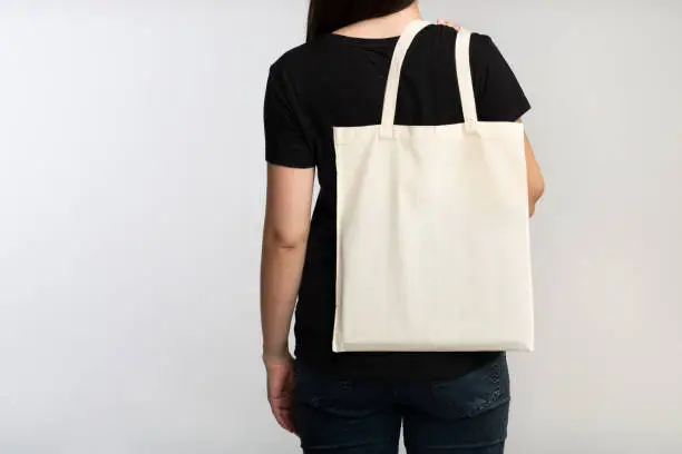 Say No To Plastic. Unrecognizable Brunette Girl Holding Eco Bag On White Studio Background. Back View, Cropped, Free Space