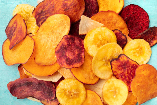 istock Dry fruit and vegetable chips, healthy vegan snack, a mixed heap on a blue background 1174443034
