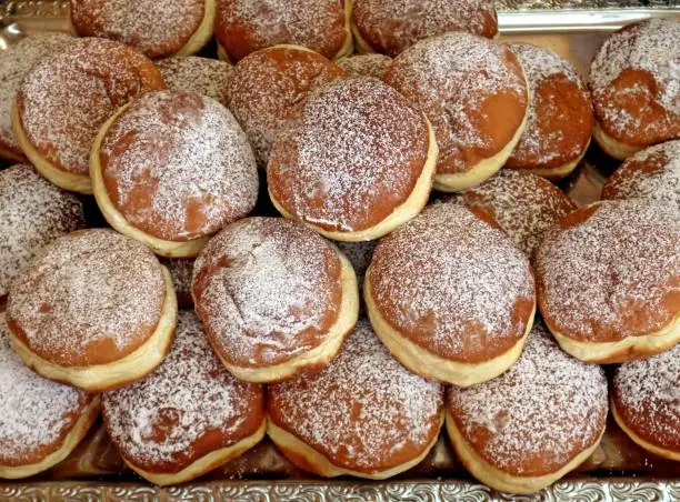 Top view of many Krapfen, also known as Berliner, on a tray of a pastry shop. It is traditional german doughnut
