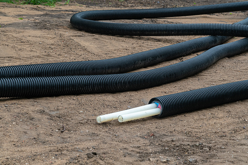 Black PVC electric pipes with wires on the ground. Construction site, power line with cable wires