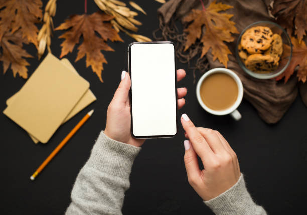 istock Woman holding cellphone with blank screen over autumn background 1174444372