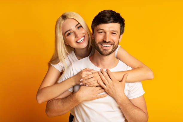 istock Smiling Couple Hugging On Yellow Studio Background 1174444577