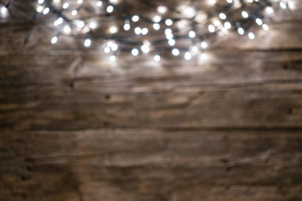 istock Empty rustic wooden table with defocused Christmas string lights at the top border 1174444583