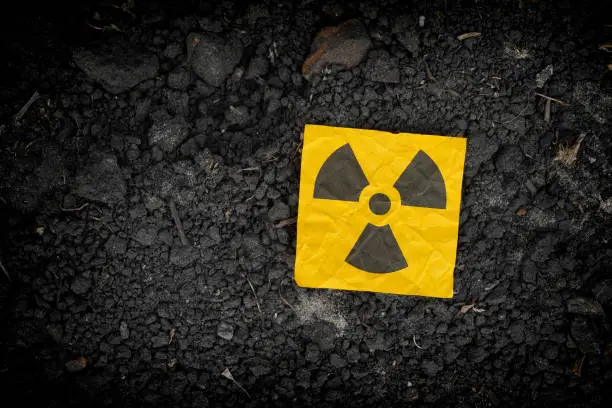 Radiation warning sign on soil background. Close up.