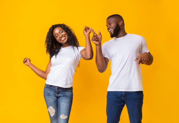 istock Young african couple dancing over yellow background 1174446989