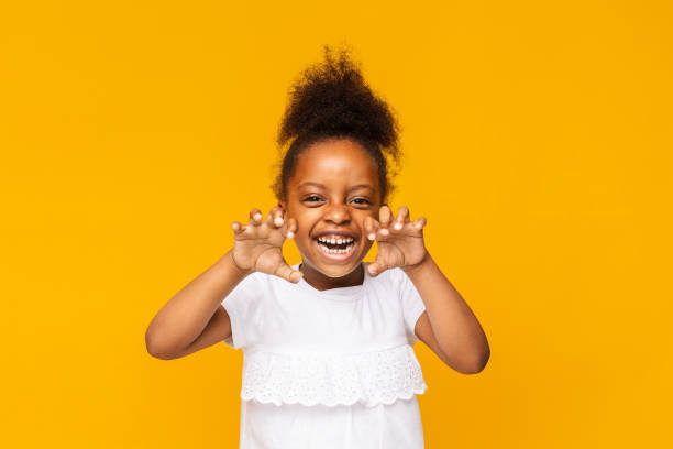 Cute playful little african girl is showing claws like tiger Funny tiger. Cute playful little african girl is showing claws, orange studio background roaring photos stock pictures, royalty-free photos & images