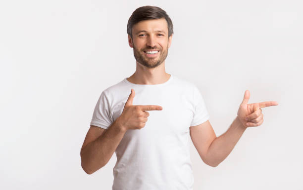 istock Smiling Guy Pointing Fingers Aside Over White Background 1174448703