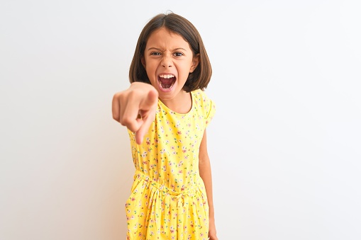 Young beautiful child girl wearing yellow floral dress standing over isolated white background pointing displeased and frustrated to the camera, angry and furious with you
