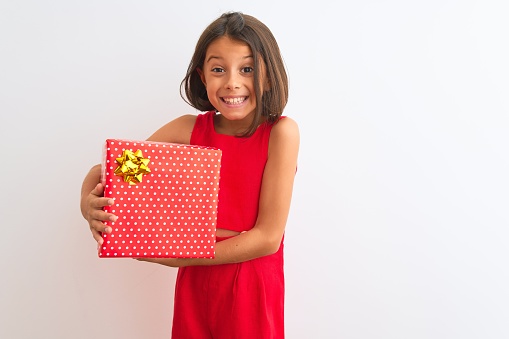 Beautiful child girl holding birthday gift standing over isolated white background with a happy face standing and smiling with a confident smile showing teeth