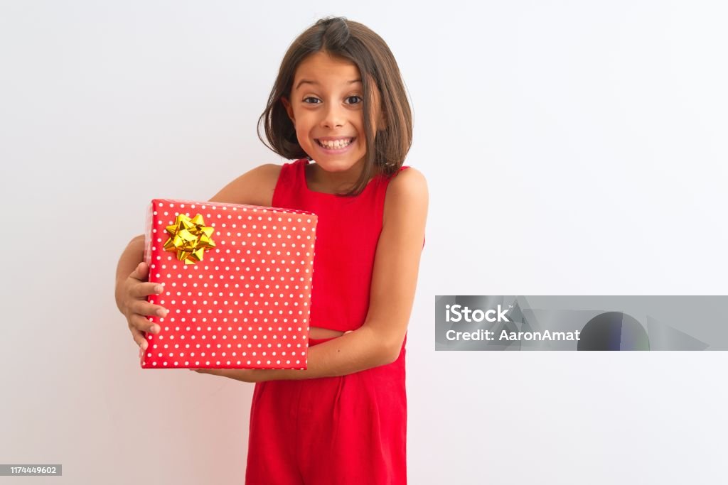 Beautiful child girl holding birthday gift standing over isolated white background with a happy face standing and smiling with a confident smile showing teeth Child Stock Photo