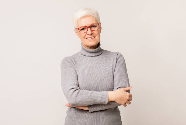 istock Confident elderly woman in glasses standing with folded arms 1174449919