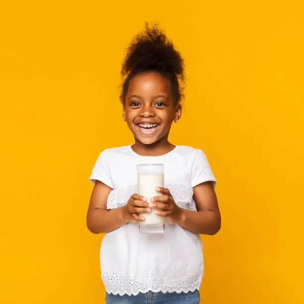 Photo of Cute afro girl enjoying glass of milk