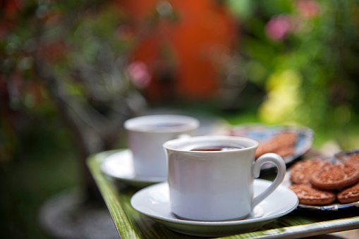 Close up photo of two cups with tea and cookies on the tray, selective focus