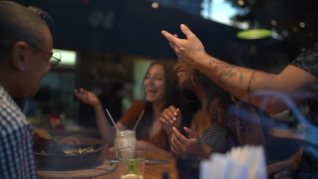 Friends laughing and having fun with mobile news at restaurant